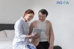 Nurse showing tablet to elderly woman