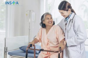 Elderly female smiling with young female doctor visiting senior patient woman at hospital ward